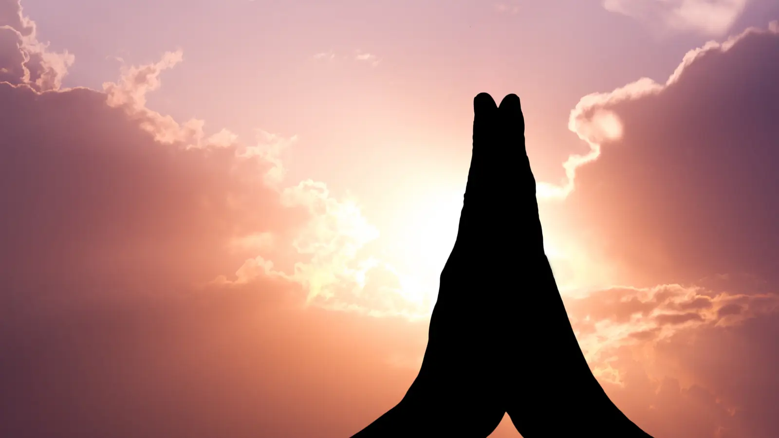 Hands joined in prayer against an evening sky